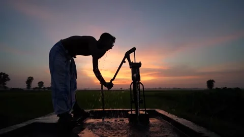 View of a man pumping water at sunset in Bogura, Bangladesh. Stock-Footage 335554080