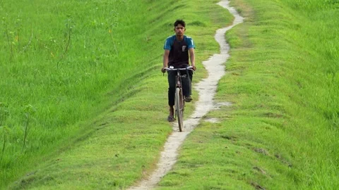 View of a man riding a bicycle through green fields, Bangladesh. Video stock 334964693
