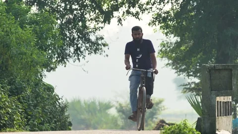 View of a man riding a bicycle through lush greenery in Bangladesh. Video stock 334970428