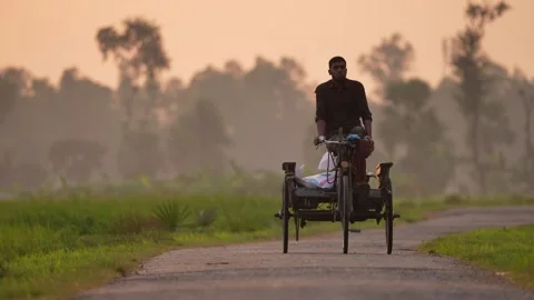 View of a man riding a cycle van on a rural road, Bangladesh. Video stock 334968801