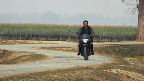 View of a man riding a motorcycle on a winding rural road, Bangladesh. Vídeo Stock 334971541