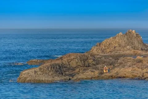 View of man sitting on the rocks reading the newspaper and sunbathing Stock Photos