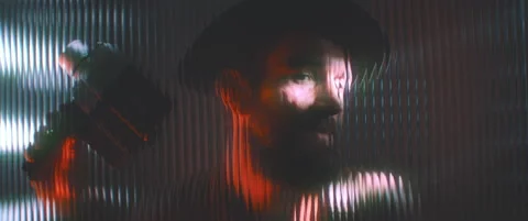 View of man through shaped clear panel in red blue lights Stock Footage 203569308