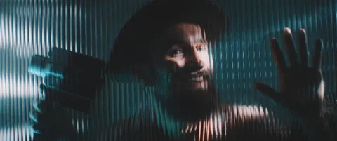 View of man through shaped clear panel in blue lights Stock Footage 203569956