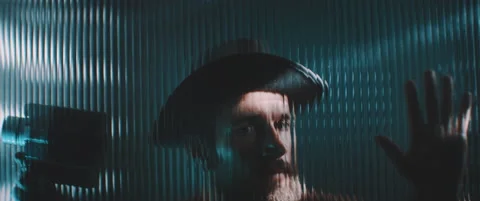 View of man through shaped clear panel in blue lights Stock Footage 203570283