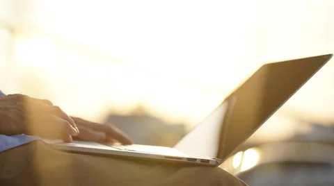 View of a man typing on computer at sunset Stock Footage 68074910