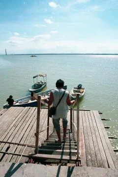 View of a man walking down the jetty stairs and a man tie a rope to secure hi Stock Photos
