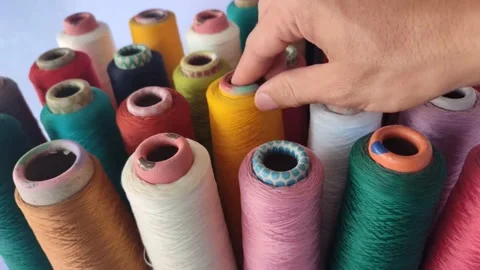 View of a man's hand putting down  a spool of Thread Stockbeeldmateriaal 225276311
