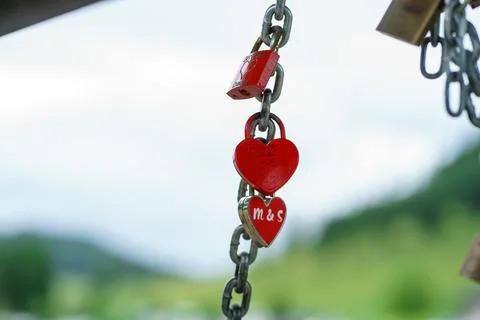 A view of many red heart-shaped padlocks hanging on a chain. Symbol of love Stock Photos