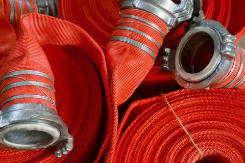 View of many twisted red fire hoses close-up in full screen. New fire Fotos de archivo