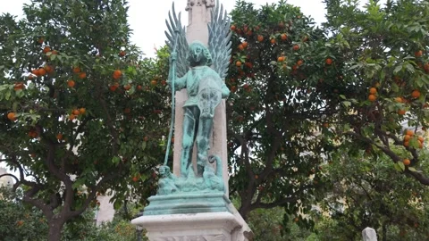 View of a medieval copper statue against a backdrop of orange trees in Spain Stock Footage 260921515