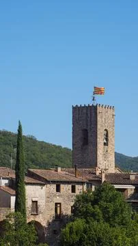 View of a medieval tower with the Catalan flag against the blue sky. Stock Photos