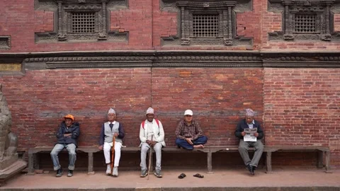 View of men sitting by a historic brick wall in Kathmandu, Nepal. 動画素材 335469789