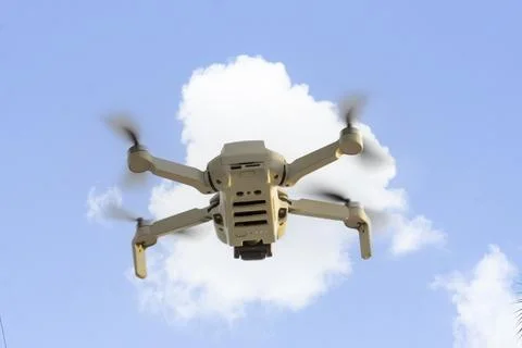 View on mini copter drone flying in the blue sky. Remote controlled drone w.. Stock Photos