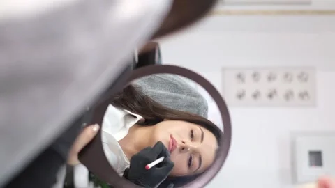 View in the mirror microblading, lip tattoo, permanent makeup. The girl at the Stock Footage 245264943