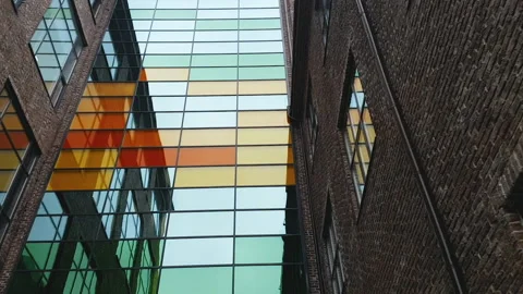 View of a modern brown brick building with colored glass elements.. Stock Footage 153289289