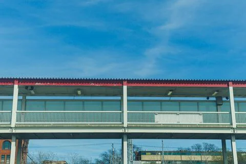 View of a modern elevated walkway against a blue sky with clouds above buil.. Фото