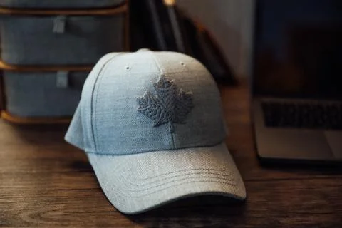 A view of a modern gray baseball cap with the design of a maple leaf on it on Stock Photos
