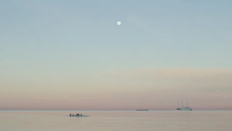 View from Molo Audace in Trieste at dawn with a full moon and kayakers Видео 339866355