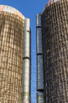 View of the moon between two tall grain silos with vines, blue sky Stock Photos