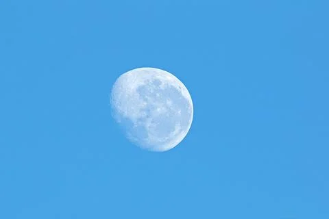 View of the moon in a cloudless, clear blue sky. Stock Photos