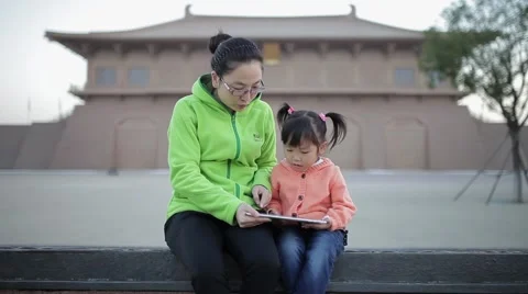 View of Mother with daughter having fun with tablet computer outdoors Stock Footage 57838996