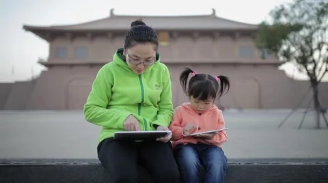View of Mother with daughter having fun with tablet computer outdoors Stock Footage 57839311