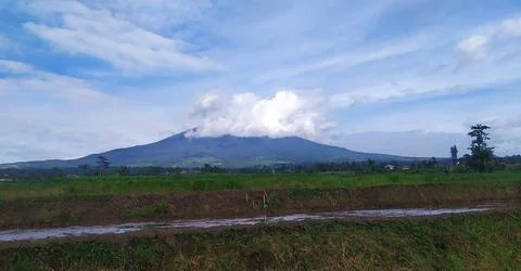 View of Mount Gede Pangrango whose peak is covered by clouds with a blue sky Stock Photos