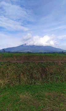 View of Mount Gede Pangrango whose peak is covered by clouds with a blue sky Stock Photos