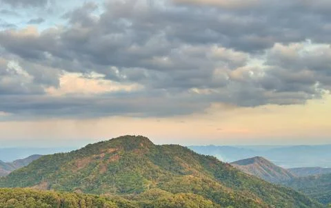 View of mountain and forest with cloudy sunset sky Stock Photos