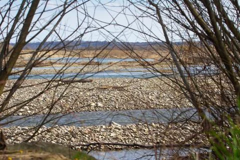 View of the mountain blue river through tree branches. Stock Photos