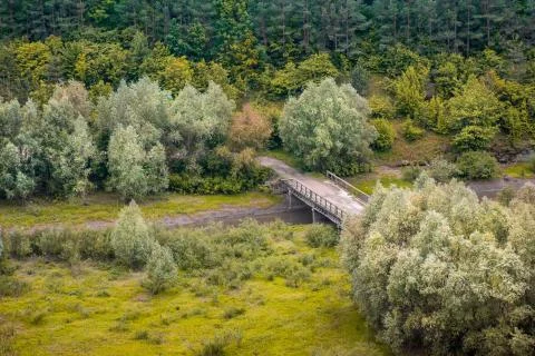 View of mountain forest and river valley with small bridge Stock Photos