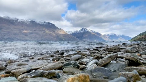 View of mountain lake waves crashing on the rocky shore Stock Footage 114669942