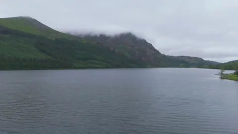 A view of a mountain with low clouds from a lake (drone shot) Stock Footage 312275891