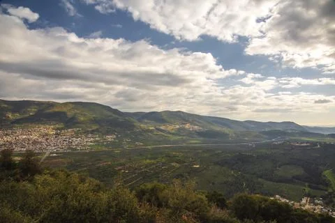 A view of a mountain range and a green valley in the morning at sunrise, against Stock Photos
