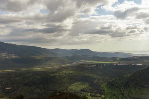 A view of a mountain range and a green valley in the morning at sunrise, against Stock Photos