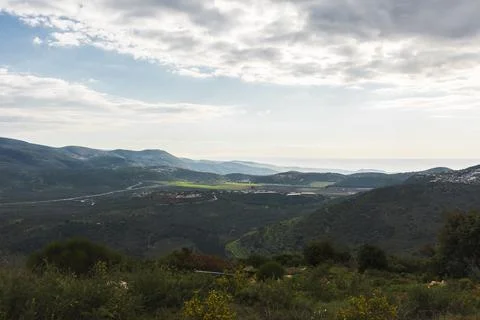A view of a mountain range and a green valley in the morning at sunrise, against Stock Photos