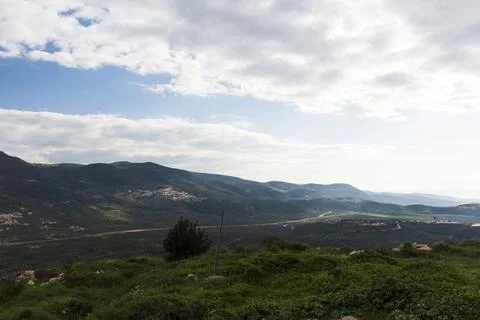 A view of a mountain range and a green valley in the morning at sunrise, against Stock Photos