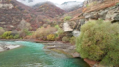 View of the mountain river with a suspension bridge and a beautiful rocky cl Stock Footage 170730547