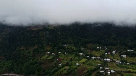 A view of a mountain with a road going through it and a few houses on the side Stock Footage 230498691