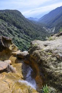 View of a mountain stream cutting through a cliff and a mountain saddle Stock Photos