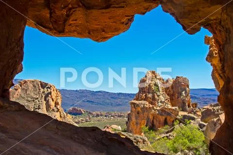 View of mountains and rocks through eroded sandstone arch Stock Photos