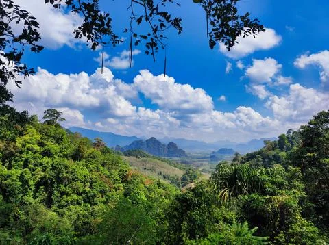 View of mountains and trees under a blue sky with clouds and sunlight durin.. Stock Photos