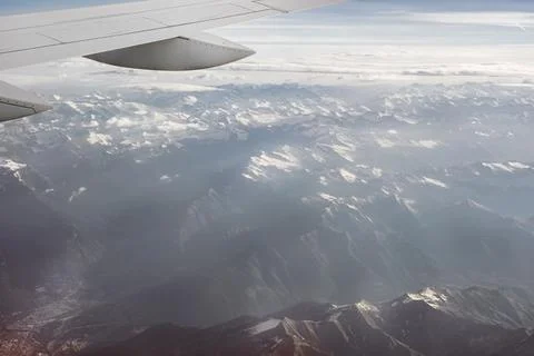 View of the mountains in snow and clouds from within, out of the plane Stock Photos