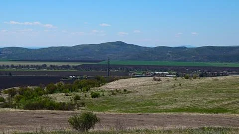 The view of a mountainside in the background of plowed fields in a valley. Stock Photos