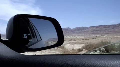 View from moving car during trip in desert, mountains in the background. 스톡 동영상 76767158