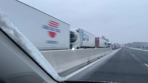 View from a moving car on a snow covered highway in France, with heavy truck Stock Footage 334044595