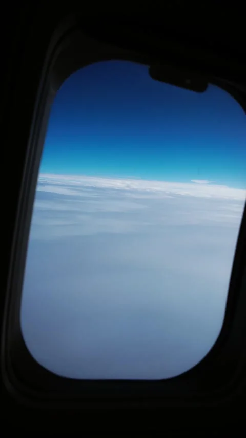 View moving through an airplane window with clouds and a clear sky Stock Footage 294291114