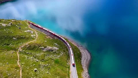 View of a moving train on the railroad through the rocky mountains by the lake	 Stock Footage 149322099