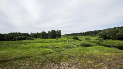 View from moving train window showing vast green fields, dense forest, calm Stockbeeldmateriaal 340387550
